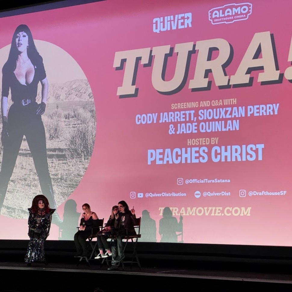 At the SF Alamo Drafthouse screening of _Tura!_, a new documentary about the life of actress/dancer/cult figure Tura Satana, a post-film chat features moderator Peaches Christ in full drag on the left; on the right are Satana's daughter Jade, Satana's manager Siouxzan Perry and doc writer/director Cody Jarrett, the latter of whom is speaking to the audience.