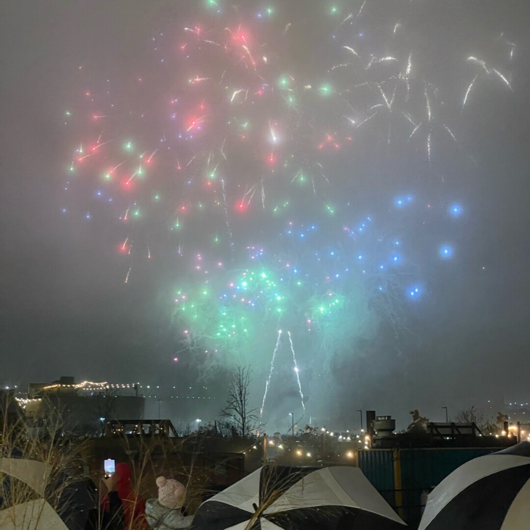 Fireworks in the fog, crowd with umbrellas watcch