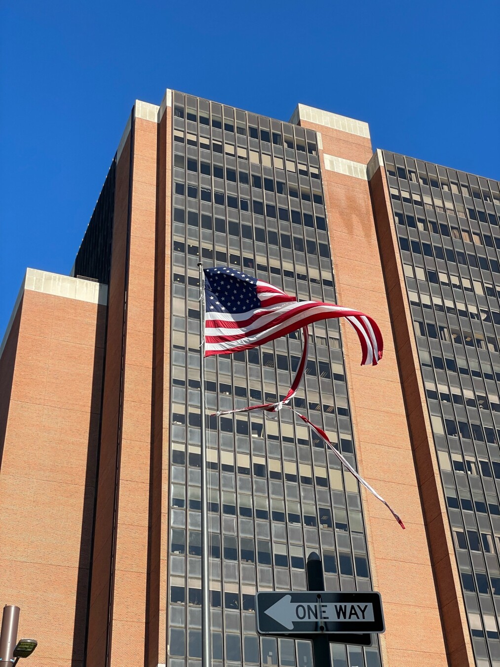 Badly tattered american flag in front of office building