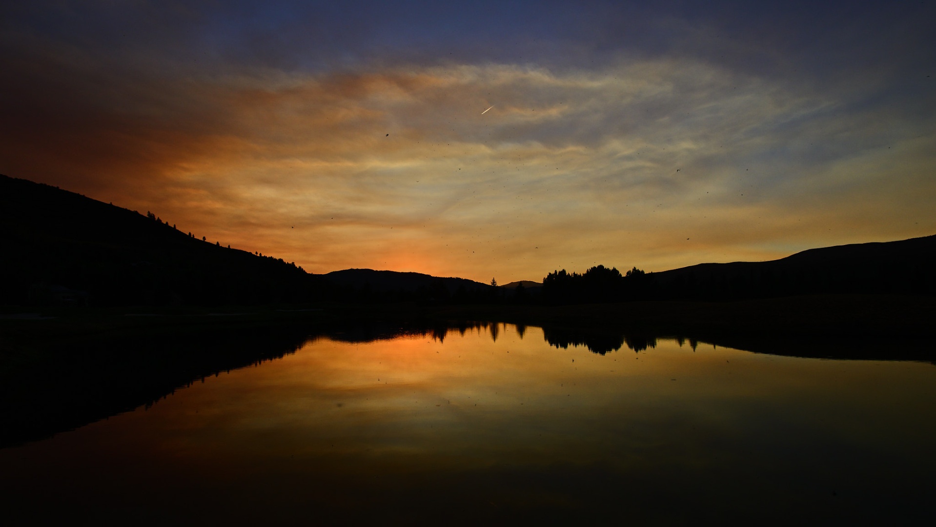 sunset over water with smoke in the air