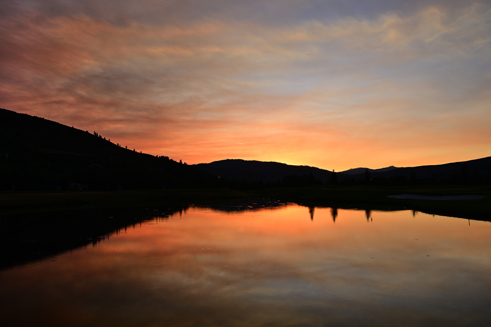 sunset over water with smoke in the sky
