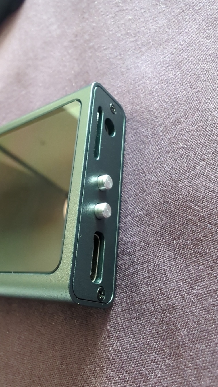 The side of the player from before, showing it's two tiny metal buttons, SD card slot, USB charging port, and 3.5mm audio jack.