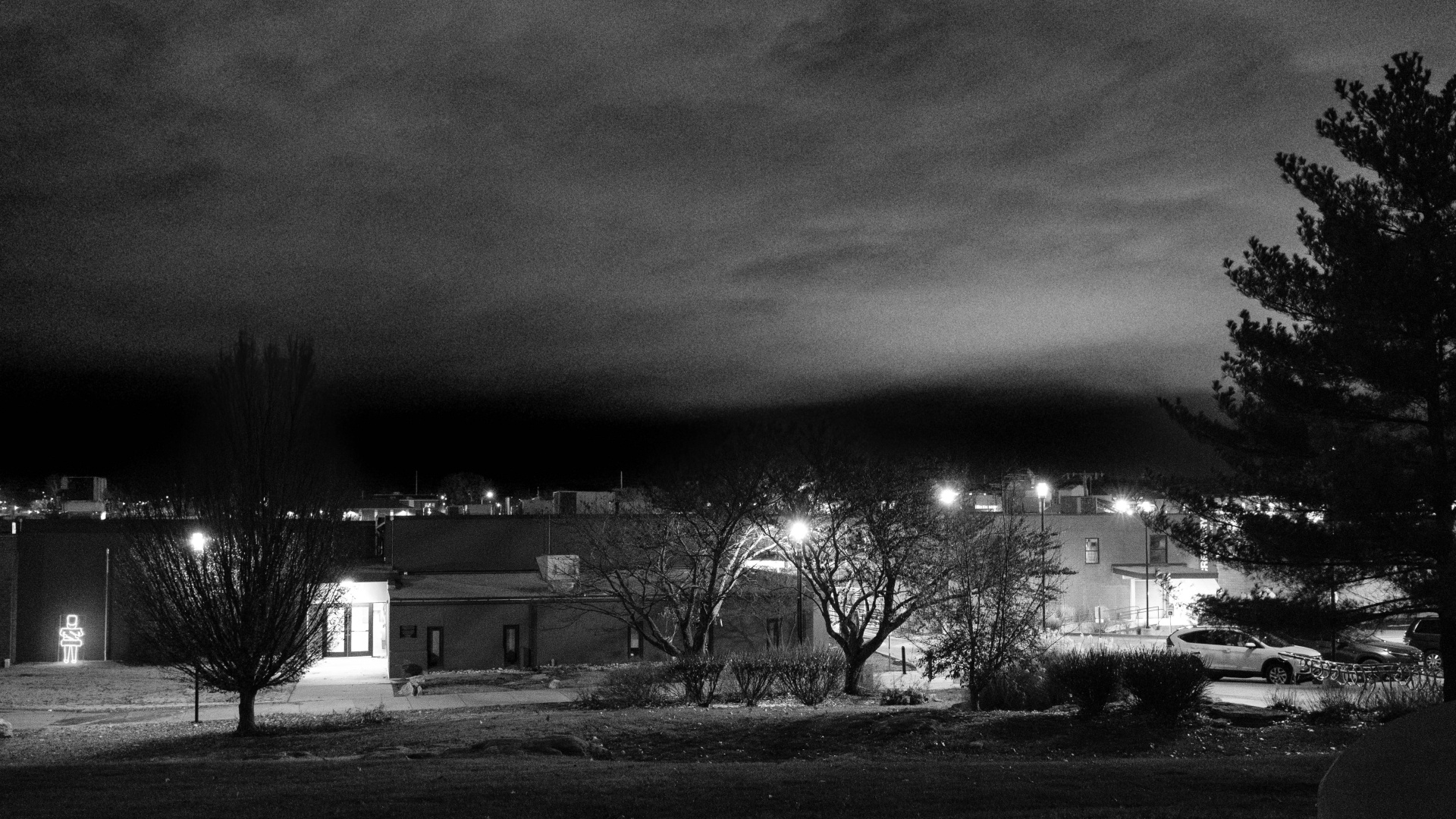 Black and white photo of a city park at night. The sky is very dramatic.